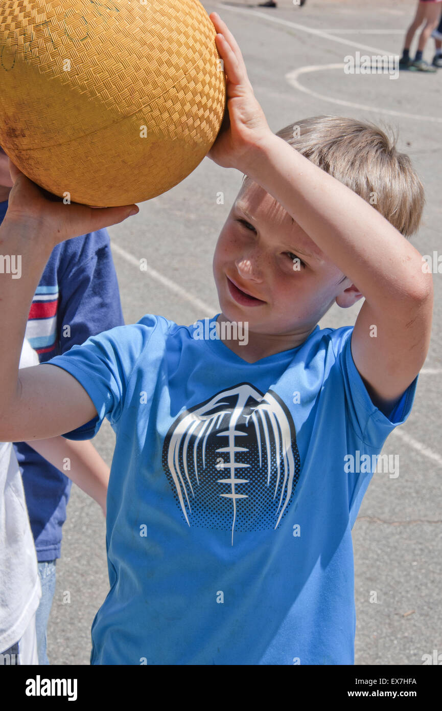 Bambino giocare a basket durante un esterno di educazione fisica classe. Foto Stock