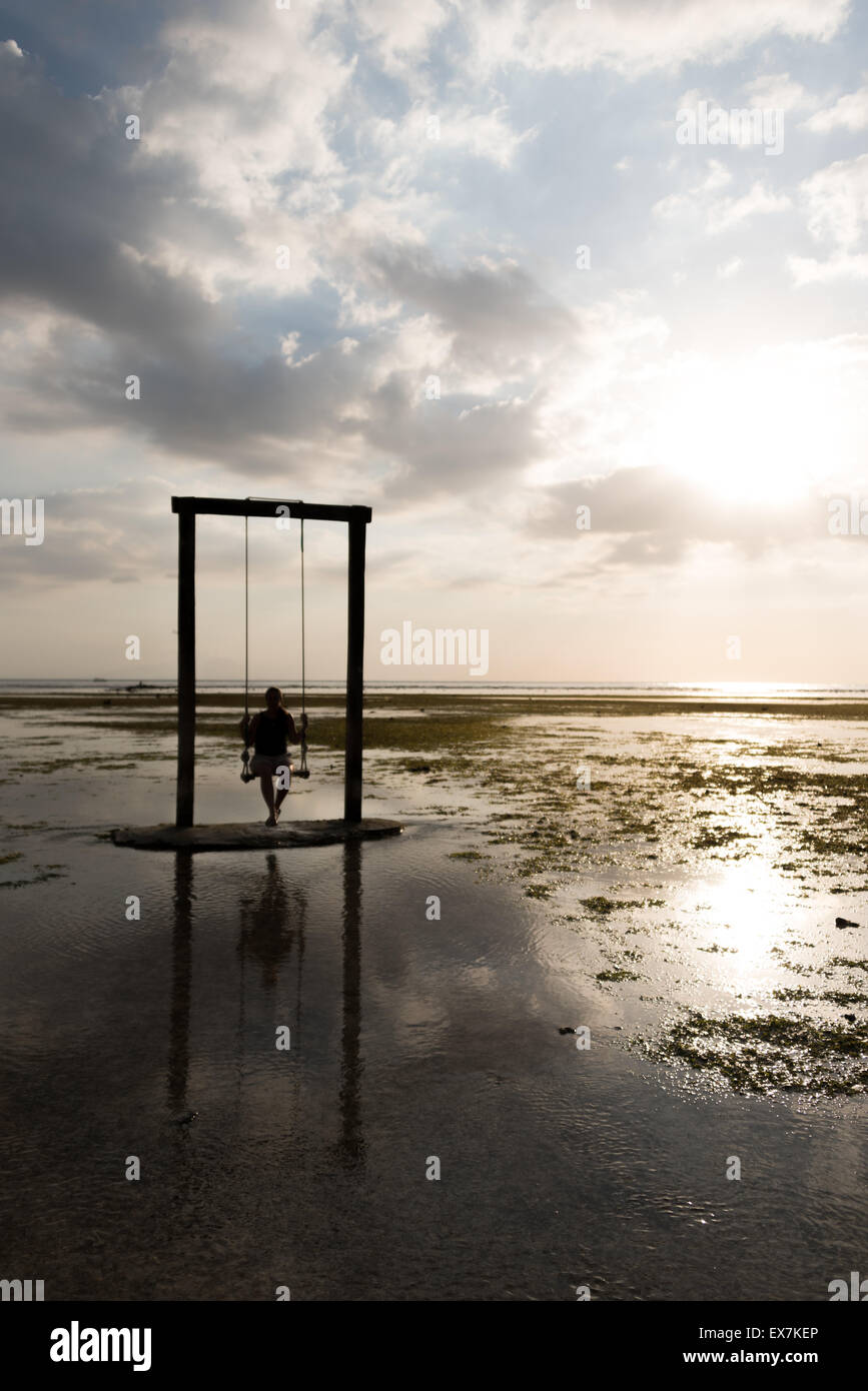 Donna sulla spiaggia swing durante il tramonto Foto Stock