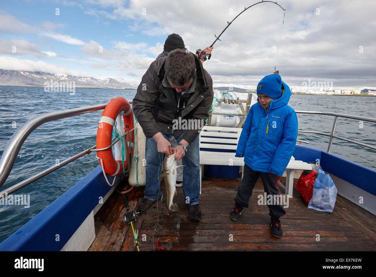 Gli uomini seafishing la cattura del pesce con un giovane ragazzo su una barca charter Reykjavik Islanda Foto Stock