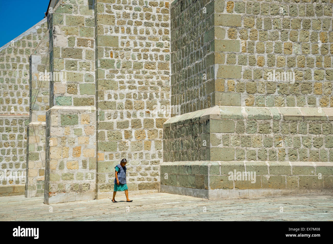 Donna con chino a piedi dalla trama parete in pietra della chiesa di solitudine in Oaxaca, Messico Foto Stock