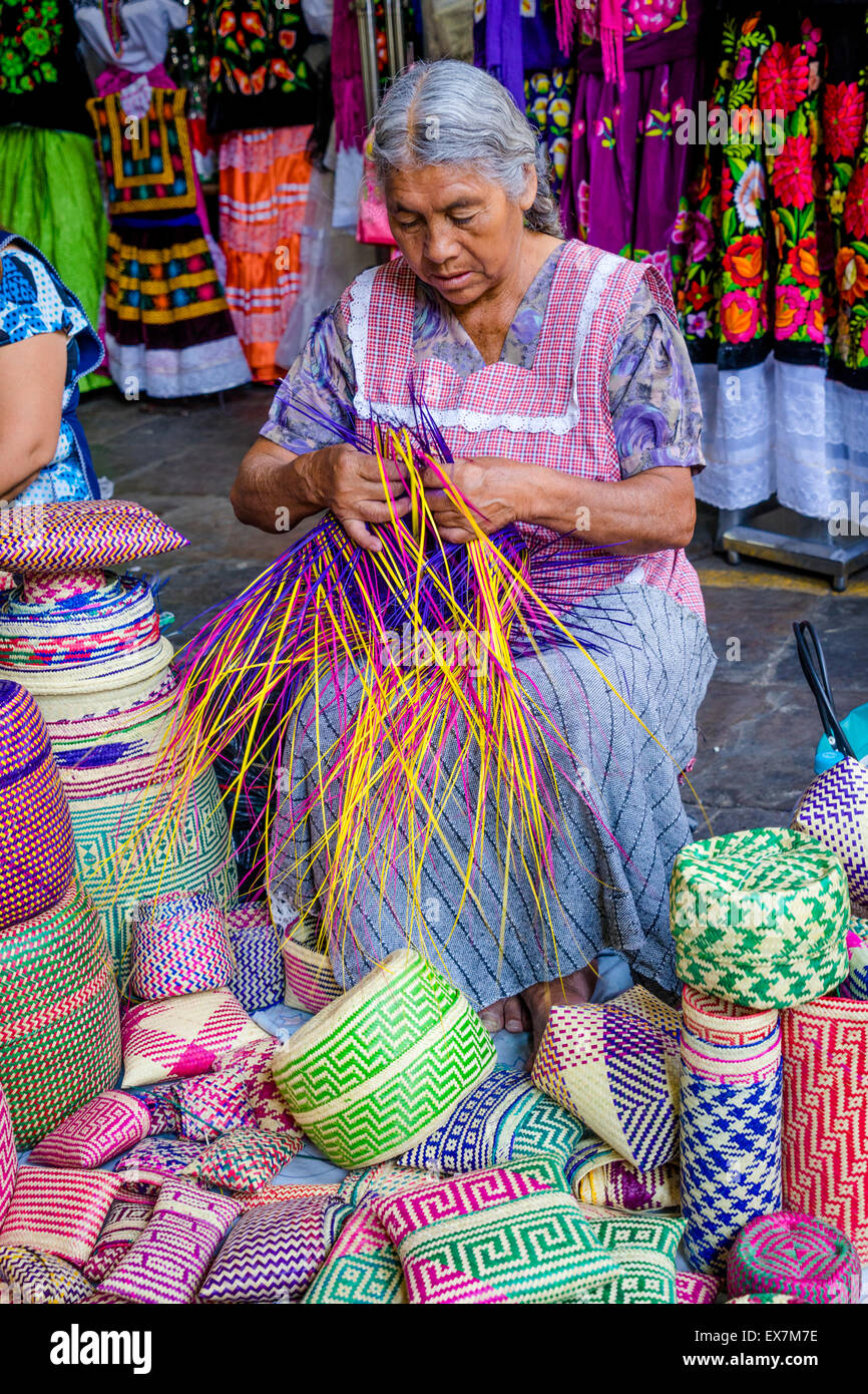 Vecchia donna rendendo tessuti tradizionali cestelli di plastica colorata strisce in una markte in Oaxaca Messico Foto Stock