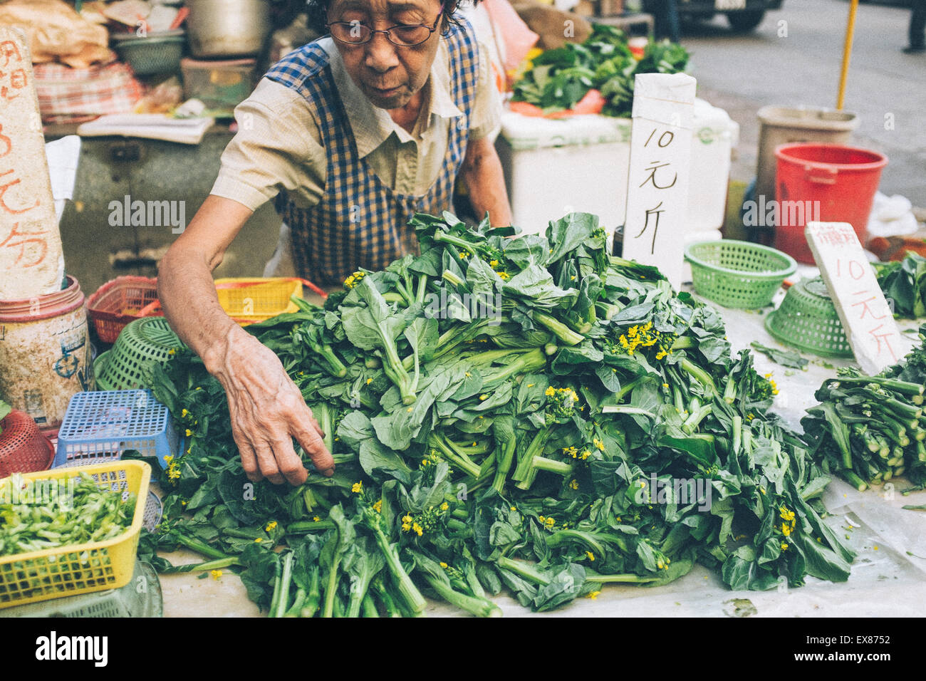 Donna venditore vegetali di vendita nel mercato di Hong Kong. Foto Stock