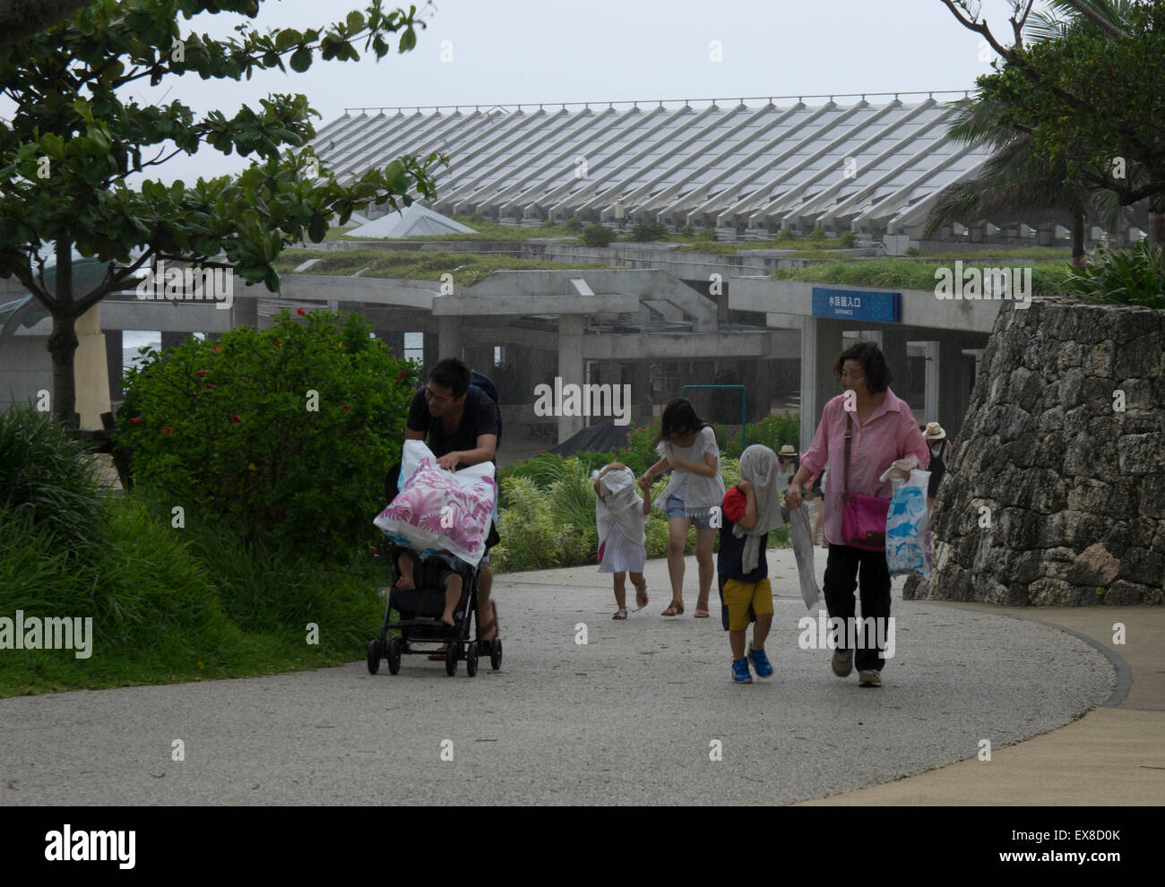 I visitatori al Churaumi Aquarium colpita da acquazzone. Typhoon Chan-hom porta il forte vento e pioggia per le isole di Okinawa, in Giappone, 9 Luglio 2015 Foto Stock