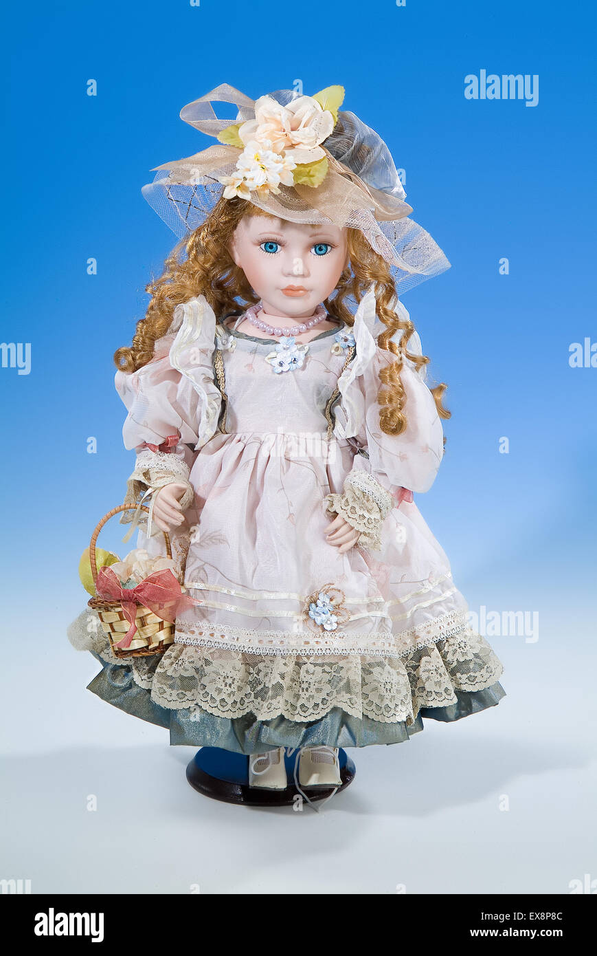 Una bambola giocattolo vestire moda ritratto persona dono infanzia retrò vintage vecchia posizione verticale oggetto sfondo bianco blu Foto Stock