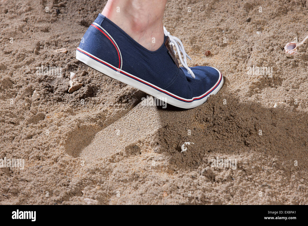 L'uomo Calzature uomo sabbia jeans denim foot print close up studio pizzo oggetto shell in pietra mare spiaggia estate vacanza di riposo a sud Foto Stock
