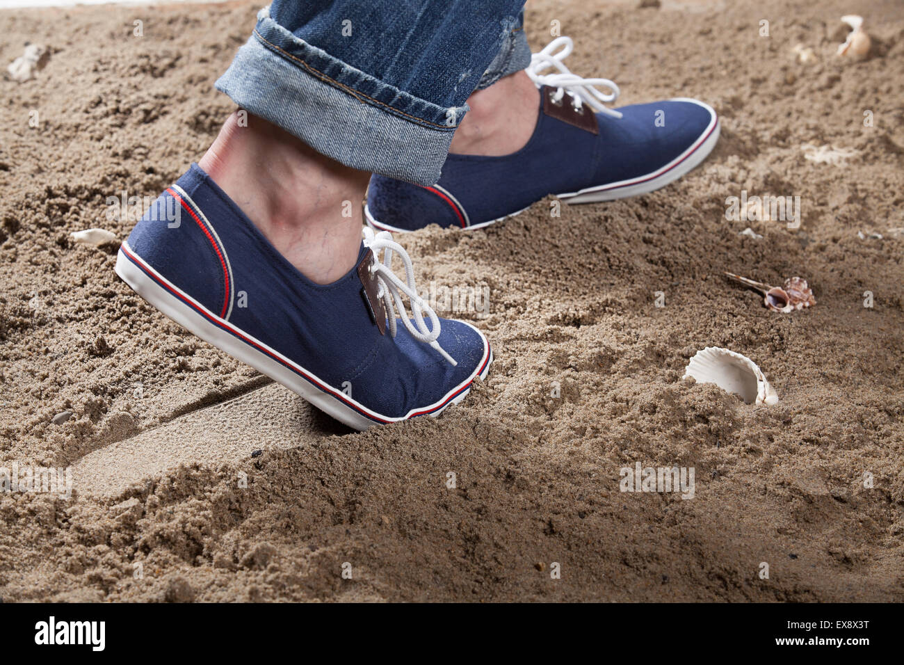 L'uomo Calzature uomo sabbia jeans denim foot print close up studio pizzo oggetto shell in pietra mare spiaggia estate vacanza di riposo a sud Foto Stock