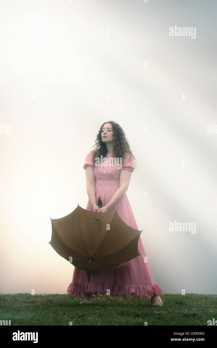 Una ragazza in un abito rosa con un ombrello Foto Stock