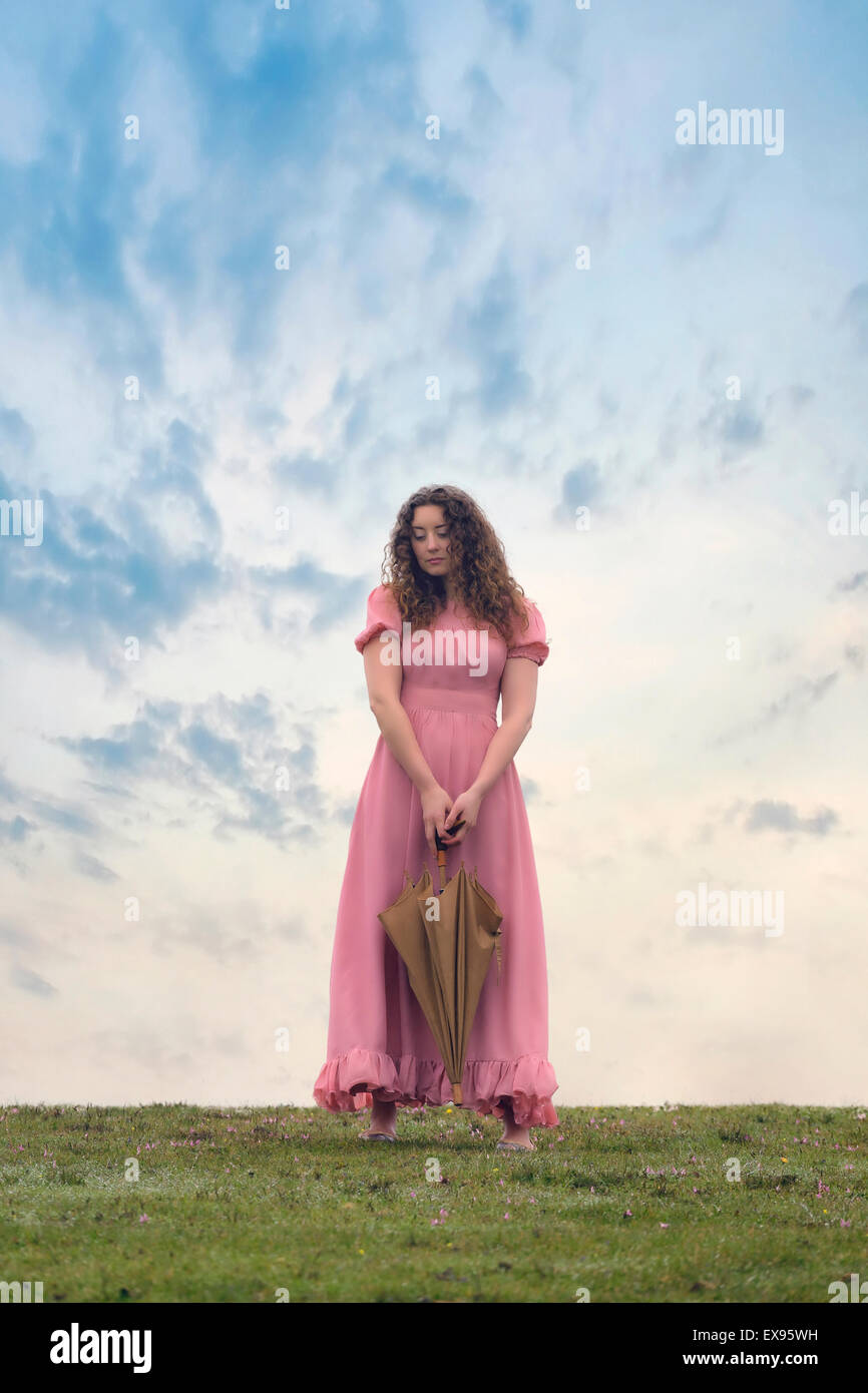 Una ragazza in un abito rosa con un ombrello Foto Stock
