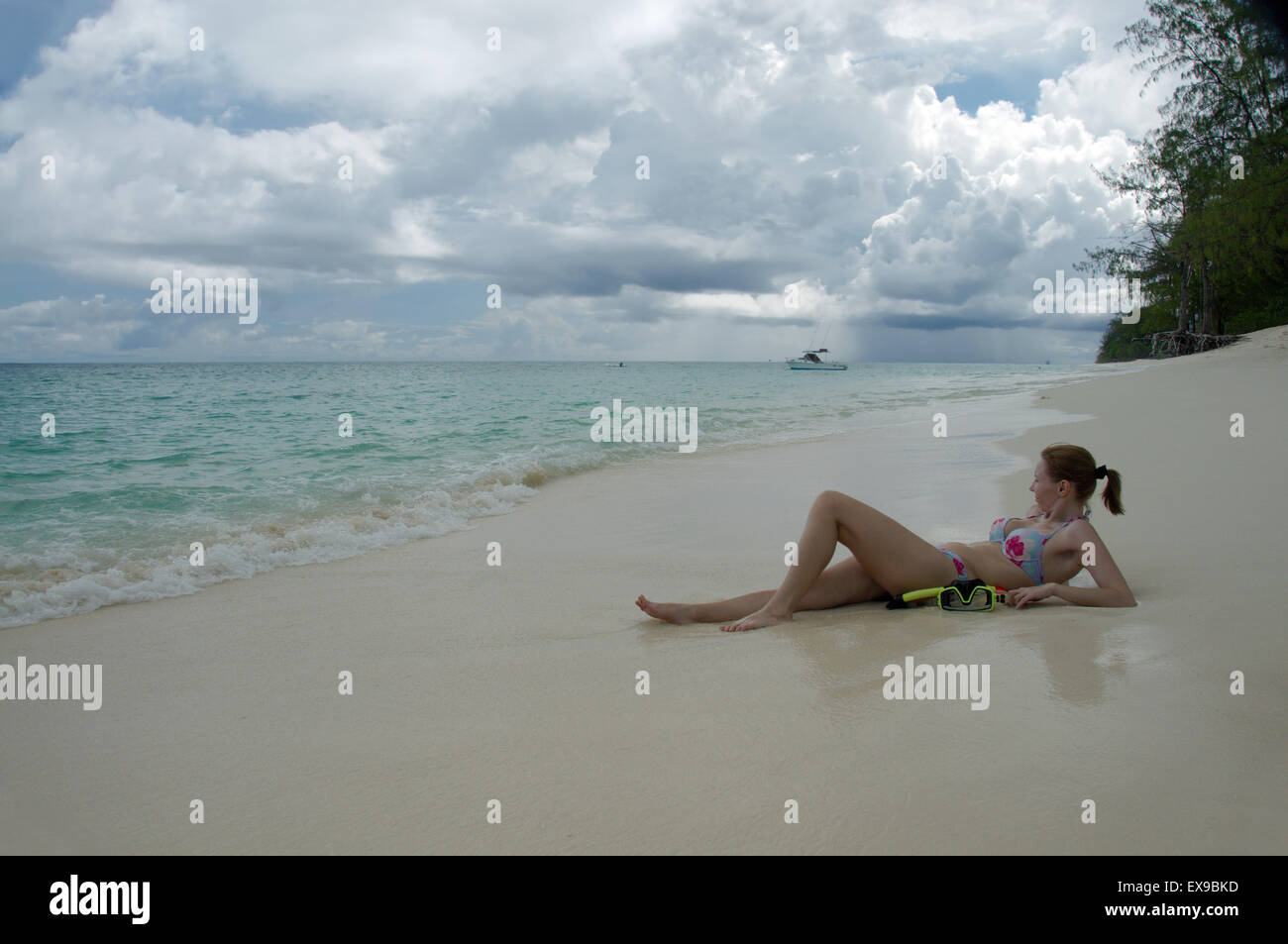 Giovane donna che giace sulle rive sabbiose dell'Oceano Indiano, Denis Island, Seicelle Foto Stock