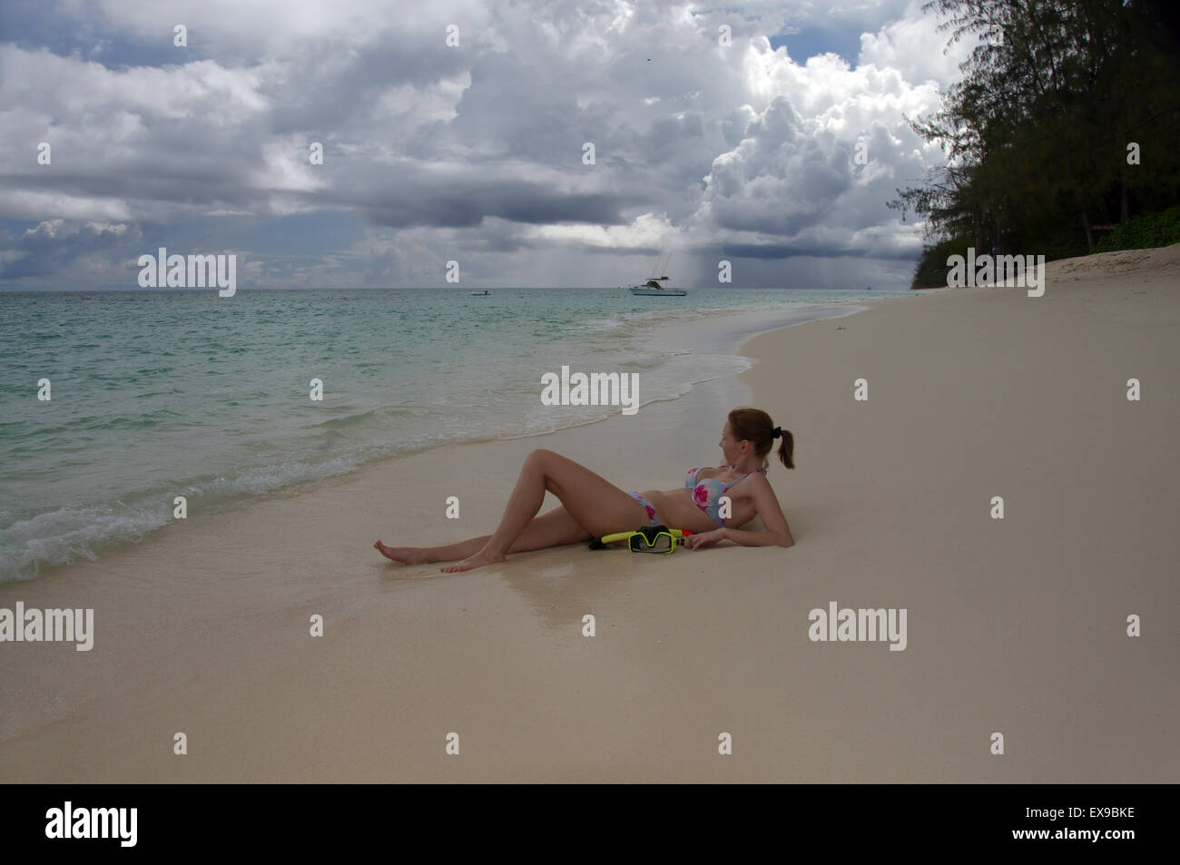 Giovane donna che giace sulle rive sabbiose dell'Oceano Indiano, Denis Island, Seicelle Foto Stock