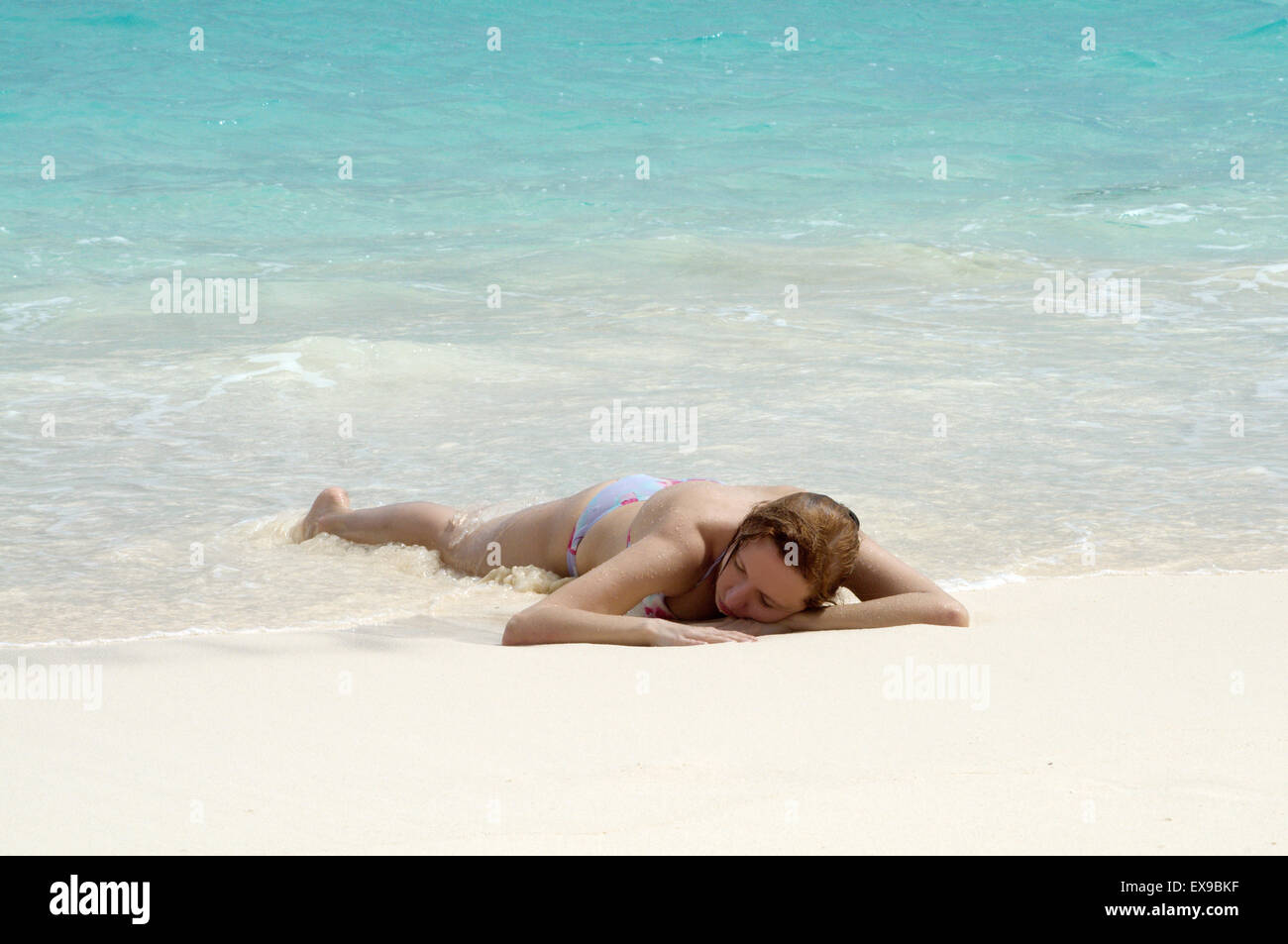Giovane donna che giace sulle rive sabbiose dell'Oceano Indiano, Denis Island, Seicelle Foto Stock