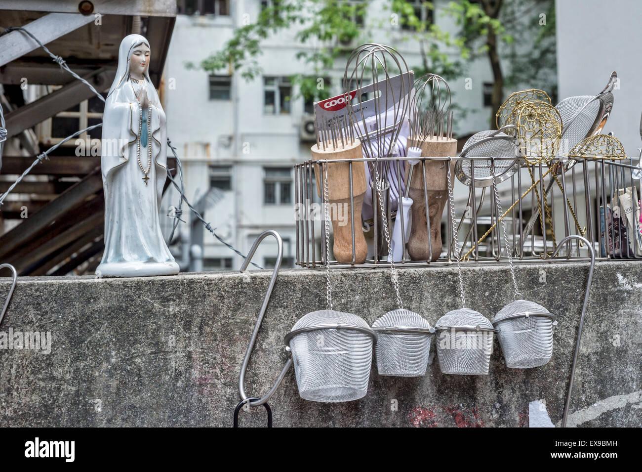 Vergine Maria statuetta accanto a tutti gli utensili da cucina, in un Hong Kong street Foto Stock