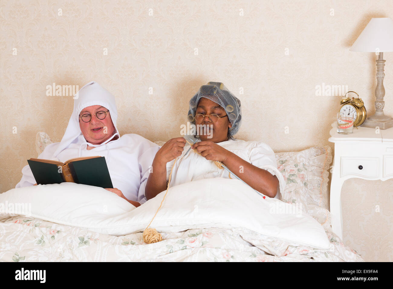 Coppia di anziani in abiti d'epoca la lettura e la maglia a letto Foto  stock - Alamy