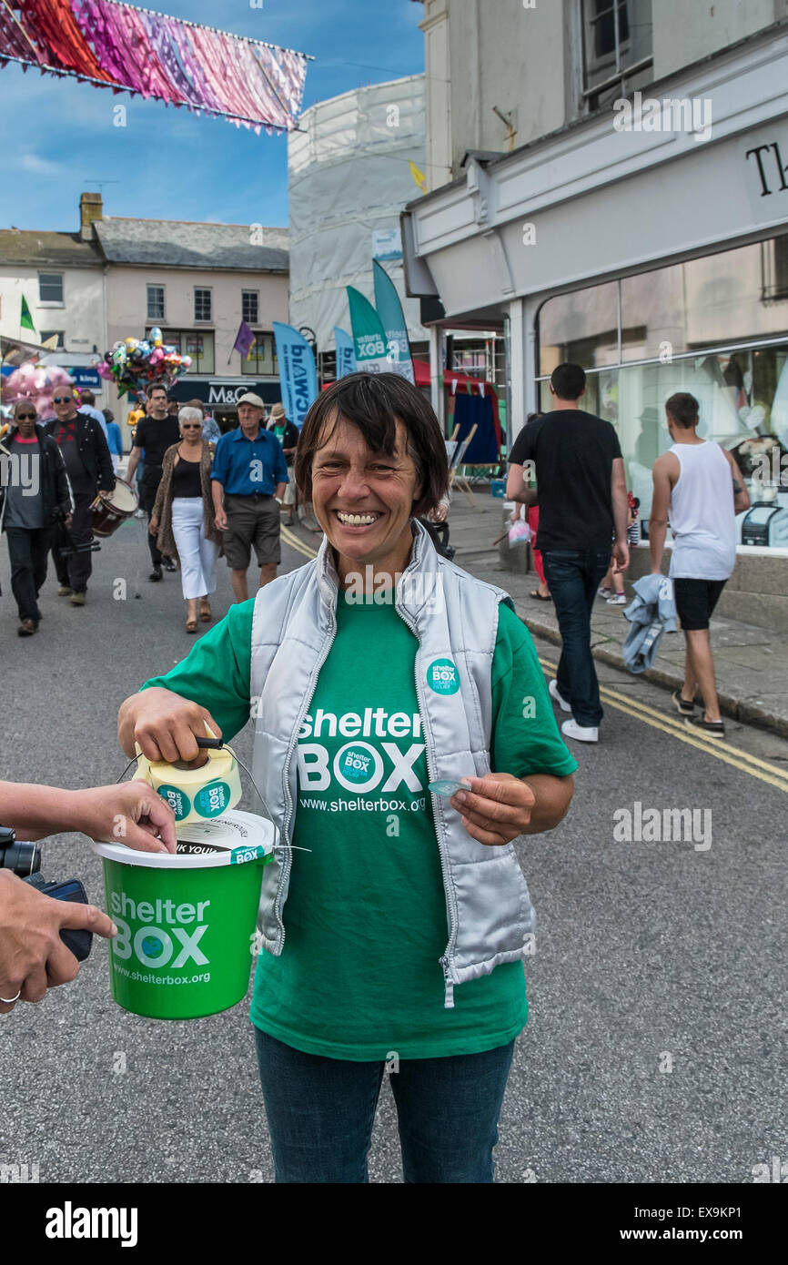 Un felice e sorridente collettore di beneficenza a raccogliere donazioni per il soccorso in caso di catastrofe carità Shelter Box in Cornovaglia, Inghilterra, Regno Unito. Foto Stock