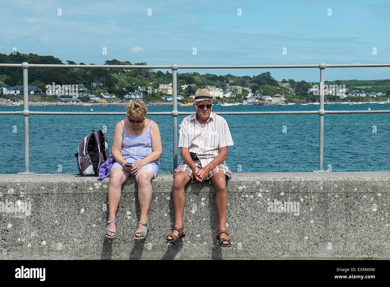 Vacanzieri seduti sulla banchina a Padstow, Cornwall. Foto Stock