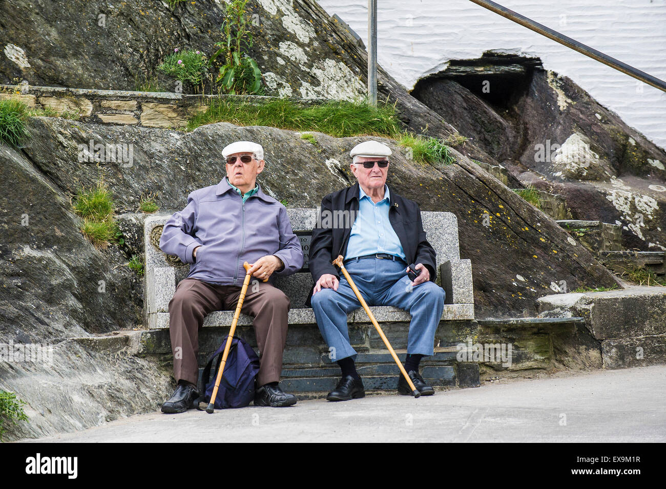 Due anziani vacanzieri seduti su una panchina nel porto di Polperro, Cornwall. Foto Stock