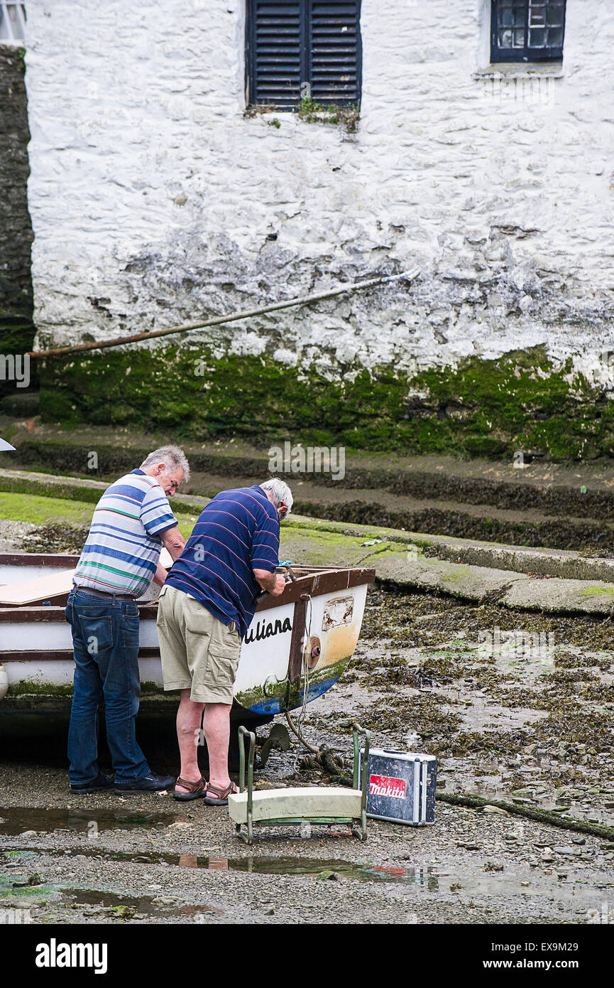 Due uomini riparare un gommone a Polperro Harbour, Cornwall. Foto Stock