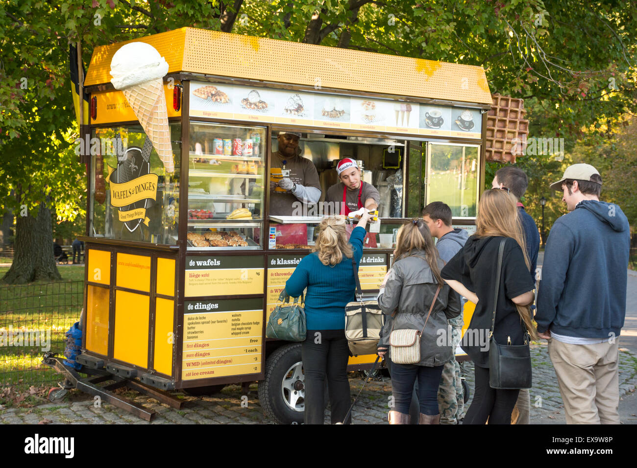 Persone in attesa in linea per cialde, in corrispondenza di un venditore ambulante di servire le cialde con varietà di condimenti in New York City Central Park Foto Stock