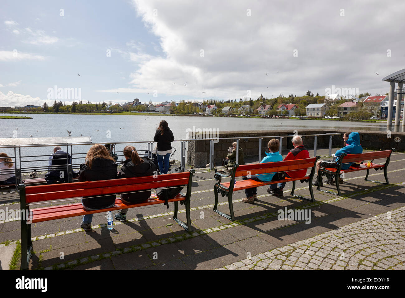 Le persone che si godono il sole estivo presso la città tjornin pond reykjavik Islanda Foto Stock