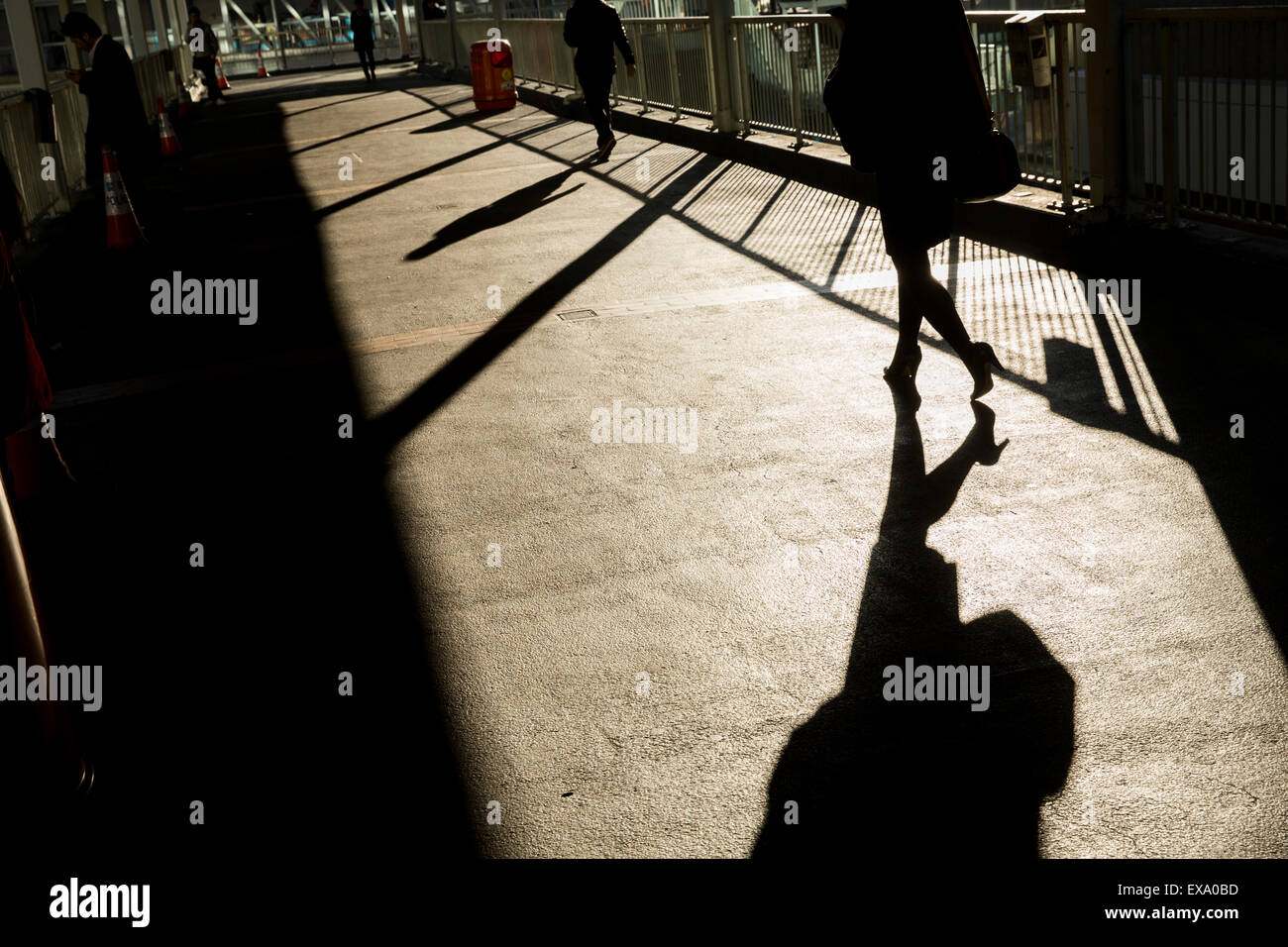 Cina, Hong Kong, ombra di donna a piedi a sunrise attraverso un ponte pedonale a Admiralty Centro sopra Connaught Road in inverno Foto Stock