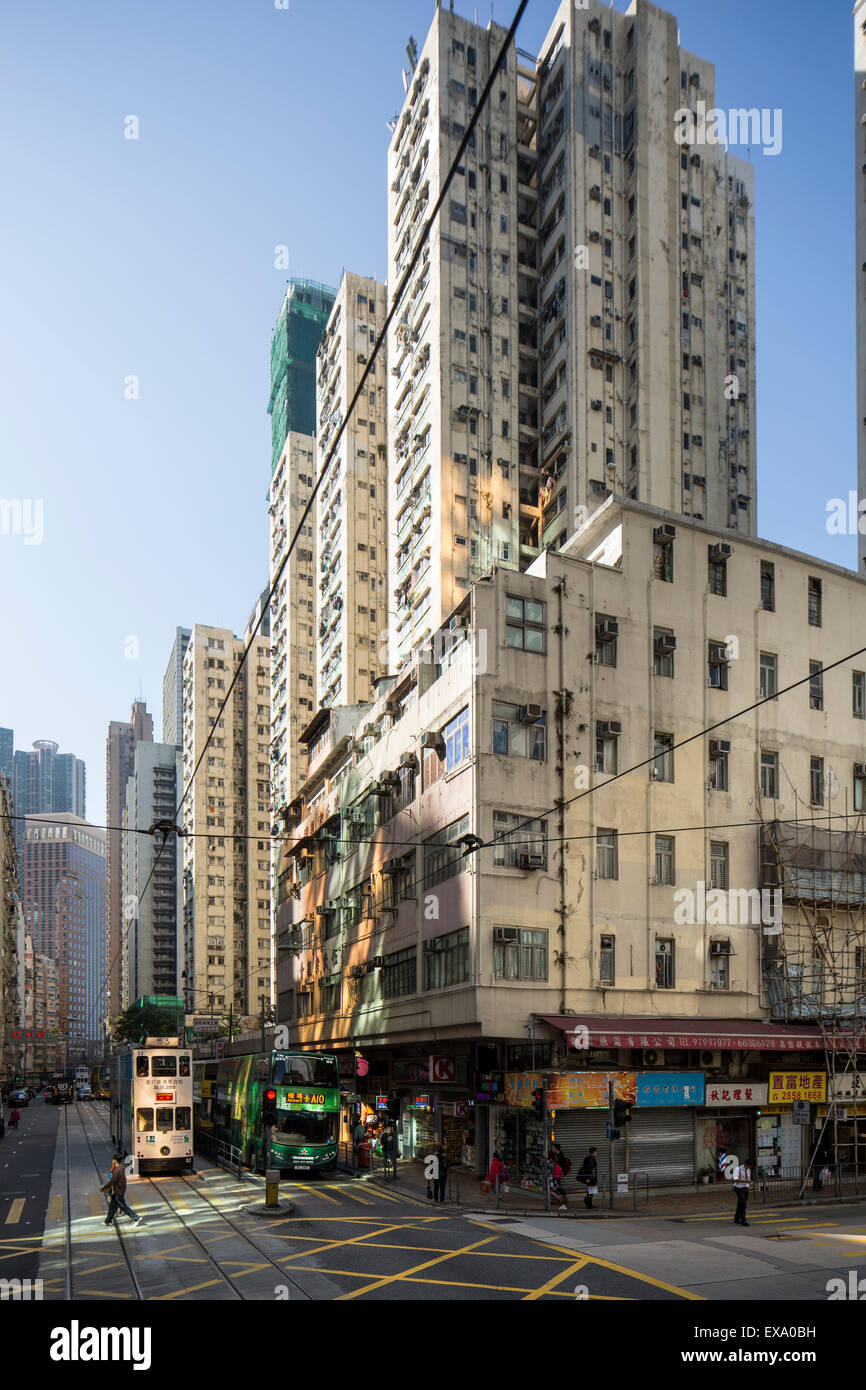 Cina, Hong Kong, tram tram guidando lungo la strada trafficata sotto le torri appartamento sul giorno di inverno Foto Stock
