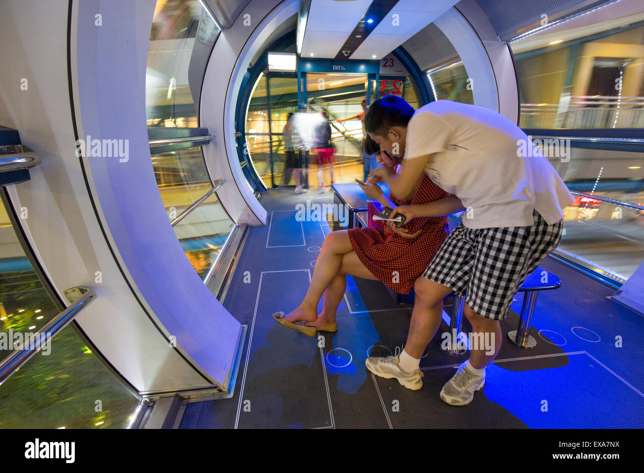 Asia, Singapore, turisti in piedi all'interno cabina del Singapore Flyer ruota panoramica che domina lo skyline della città di notte Foto Stock