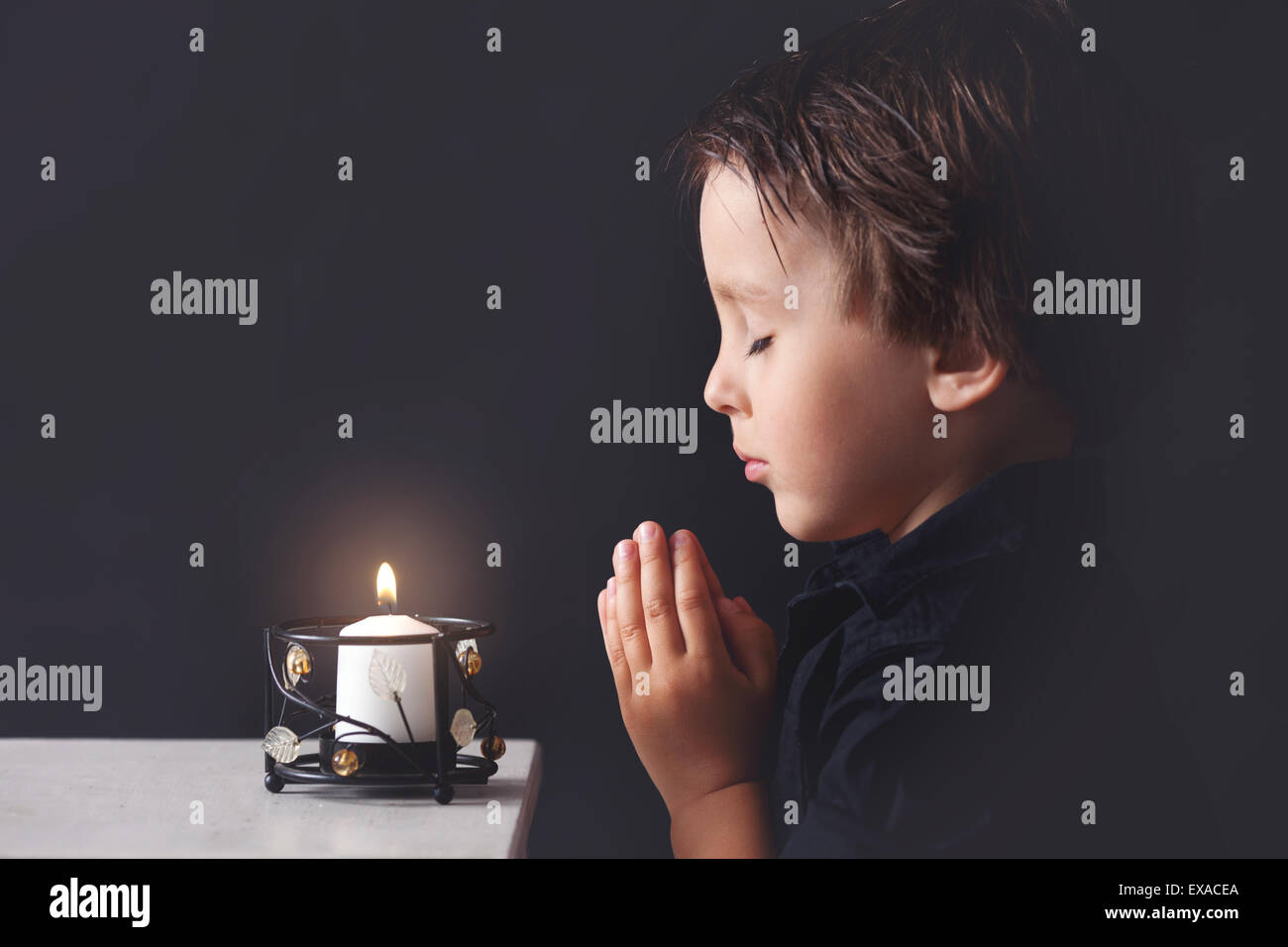 Little Boy pregando, bambino orante, isolato su sfondo nero Foto Stock