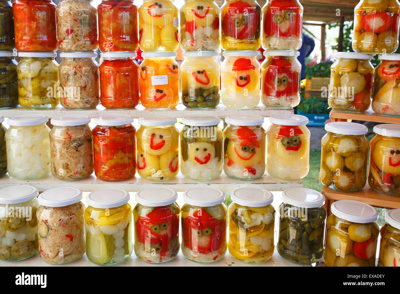 I peperoncini sott'aceto, i cetrioli, le cipolle e altre verdure in bicchieri con facce buffe, mercato di agricoltori sul lago di Balaton, Ungheria Foto Stock