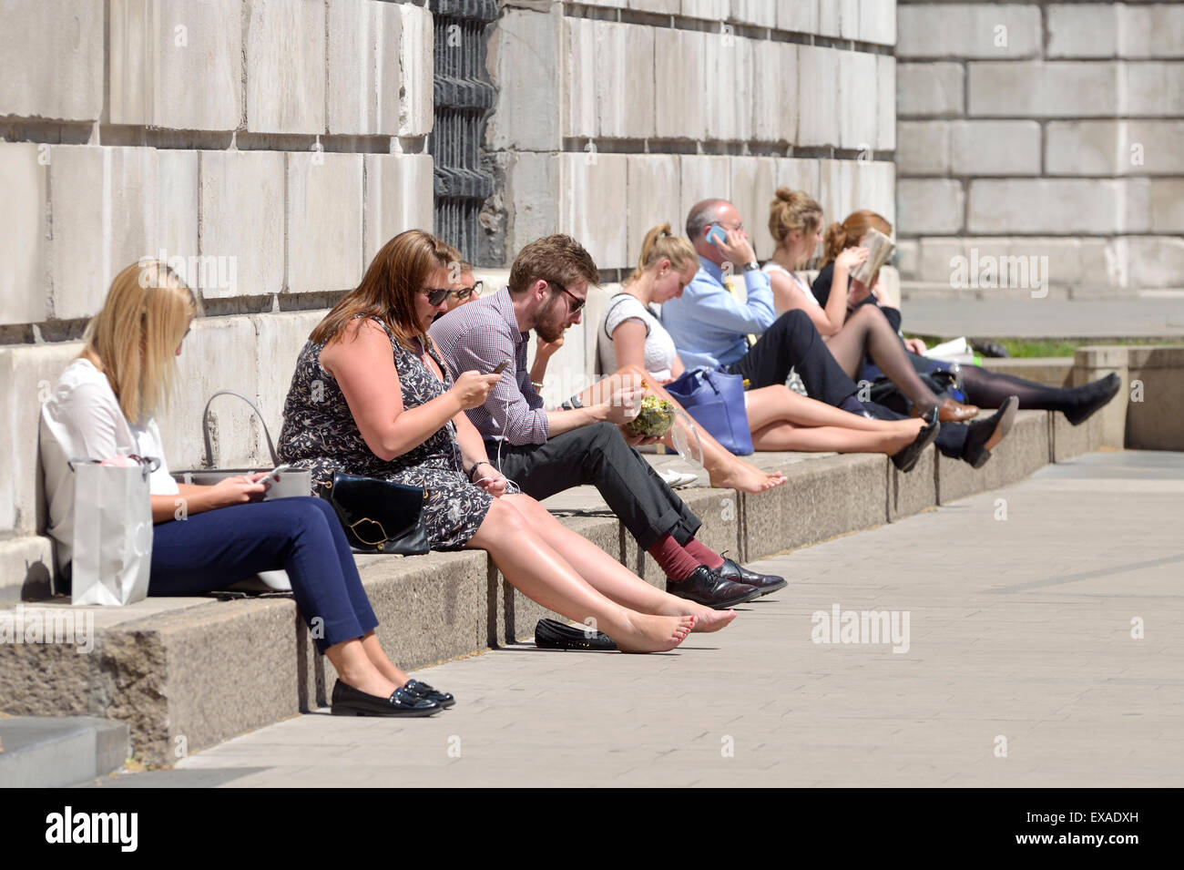 Londra, Inghilterra, Regno Unito. La gente seduta nel giardino della Cattedrale di San Paolo durante la loro ora di pranzo in una giornata di sole in giugno Foto Stock