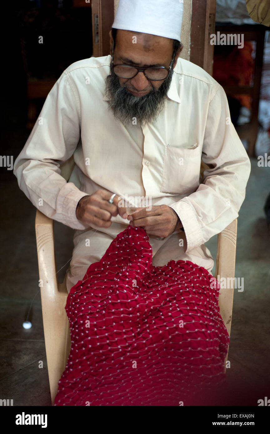 Uomo musulmano, esperto bhandani tie-dye master, preciso di legatura piccoli nodi in seta rossa, Mandvi, Gujarat, India Foto Stock