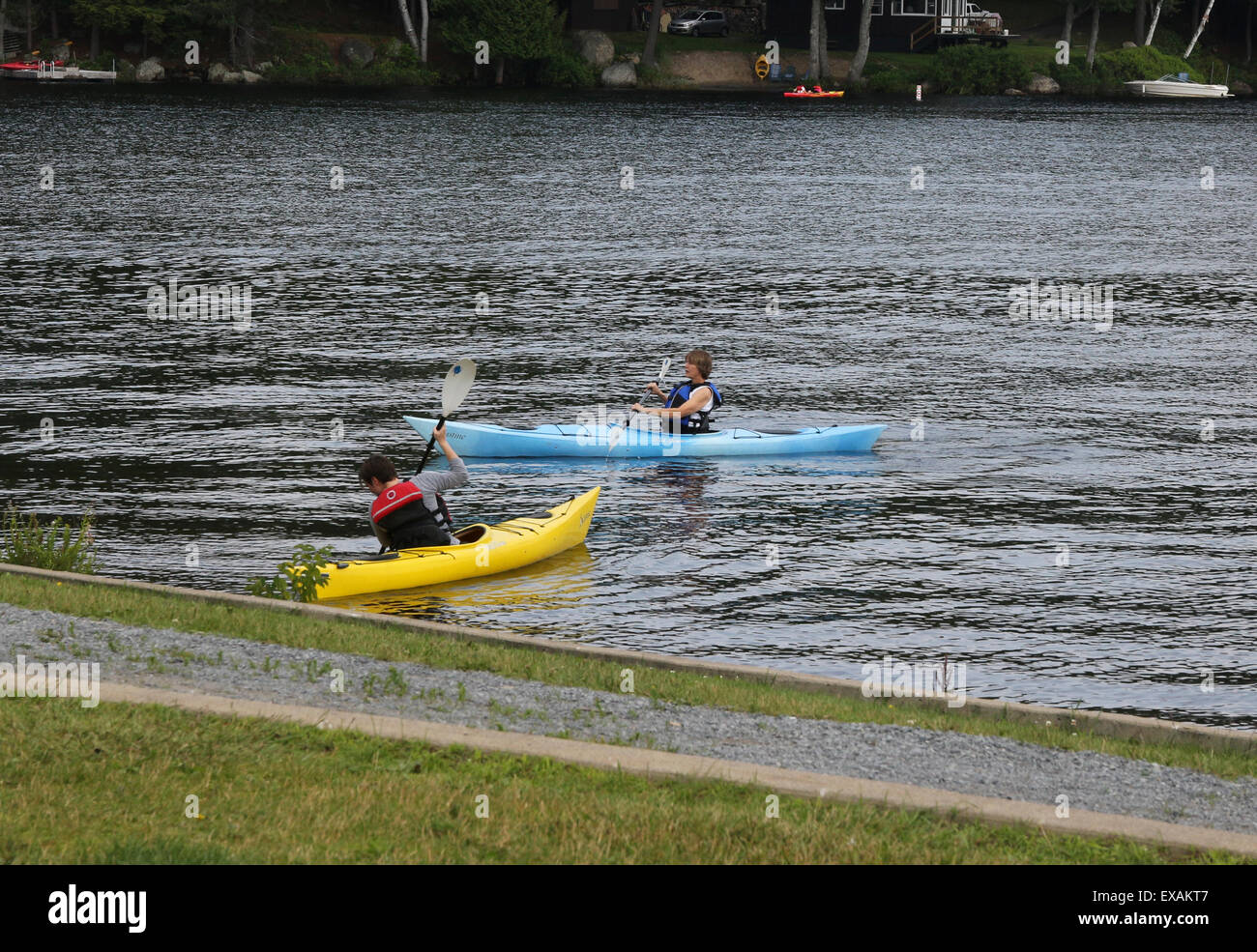 Due ragazzi in due kayak paddling vicino al litorale spiaggia a lungo lago New York Adirondack State Park USA USA, America Foto Stock