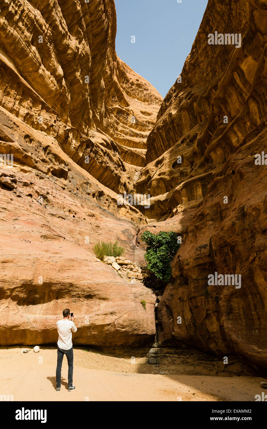 Il Wadi Rum, Giordania. Maschio turistica europea fotografare la formazione rocciosa naturale nel deserto. Foto Stock