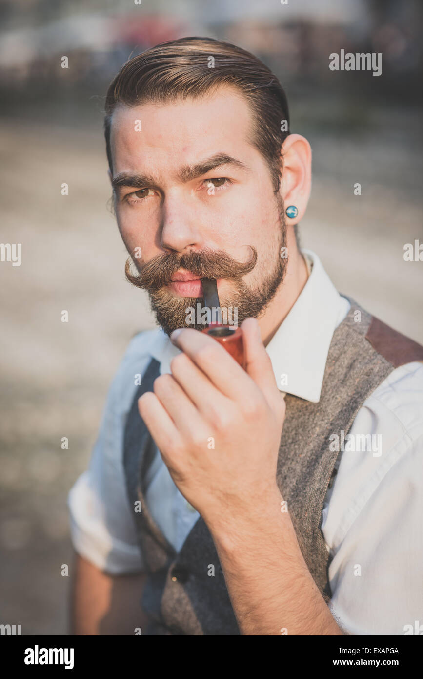 Bello grandi baffi hipster uomo tubo di fumo nella città Foto Stock