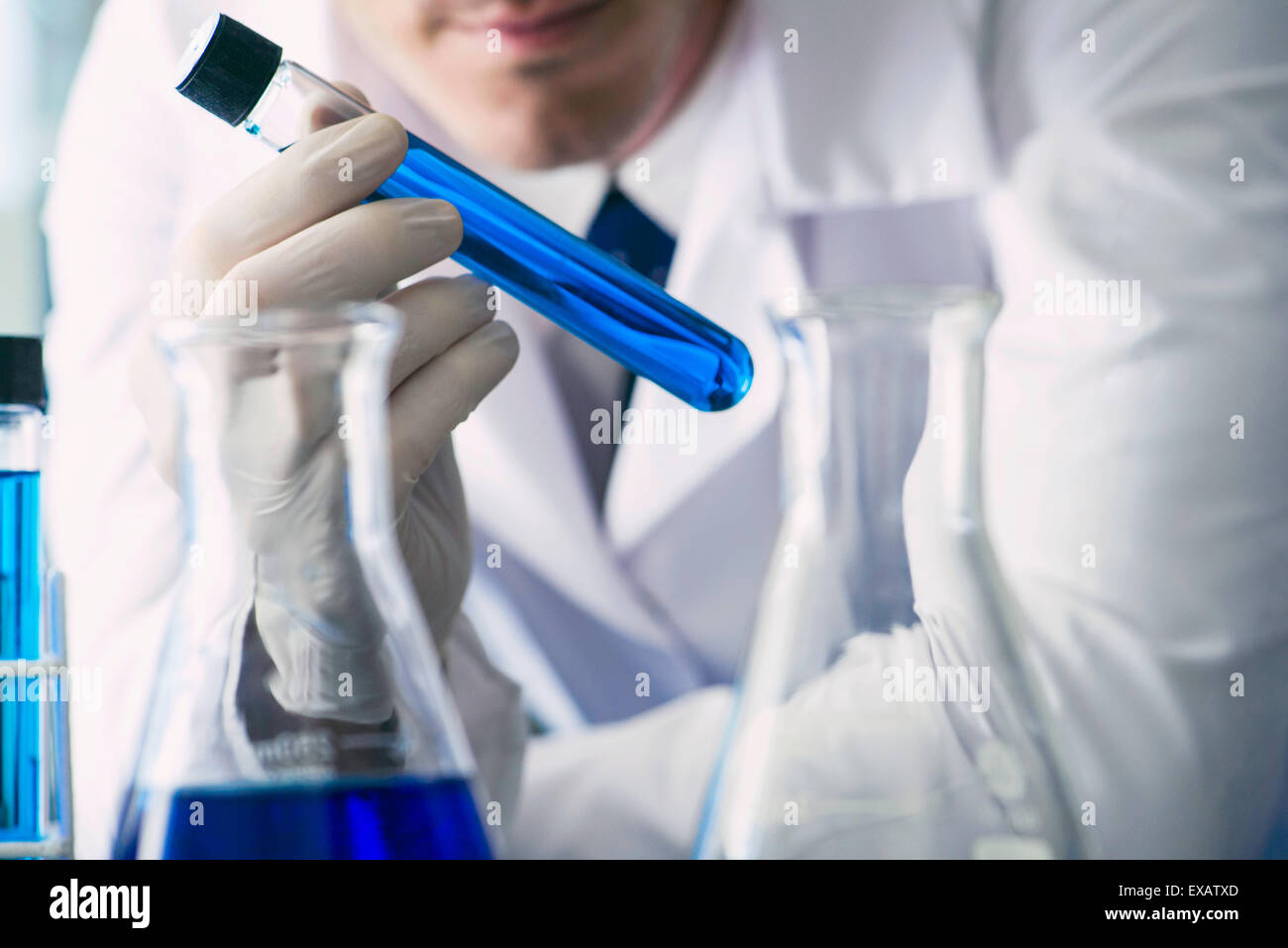 Farmacia esaminando provetta contenente liquido blu, ritagliato Foto Stock