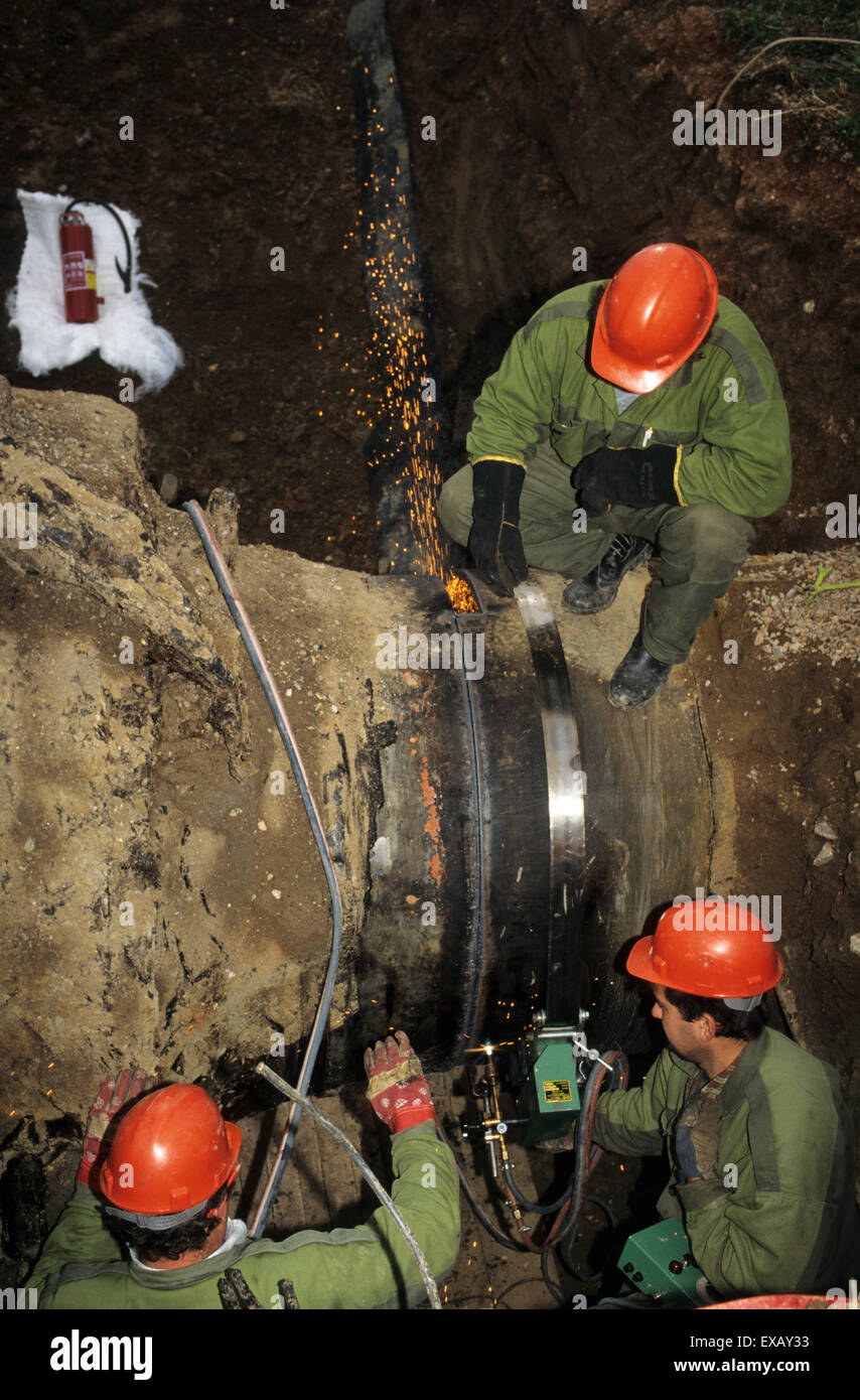 La Slovacchia: i lavoratori in tuta verde e rosso duro cappelli il taglio di una pipeline di gas utilizzando una apparecchiatura di taglio. Foto Stock