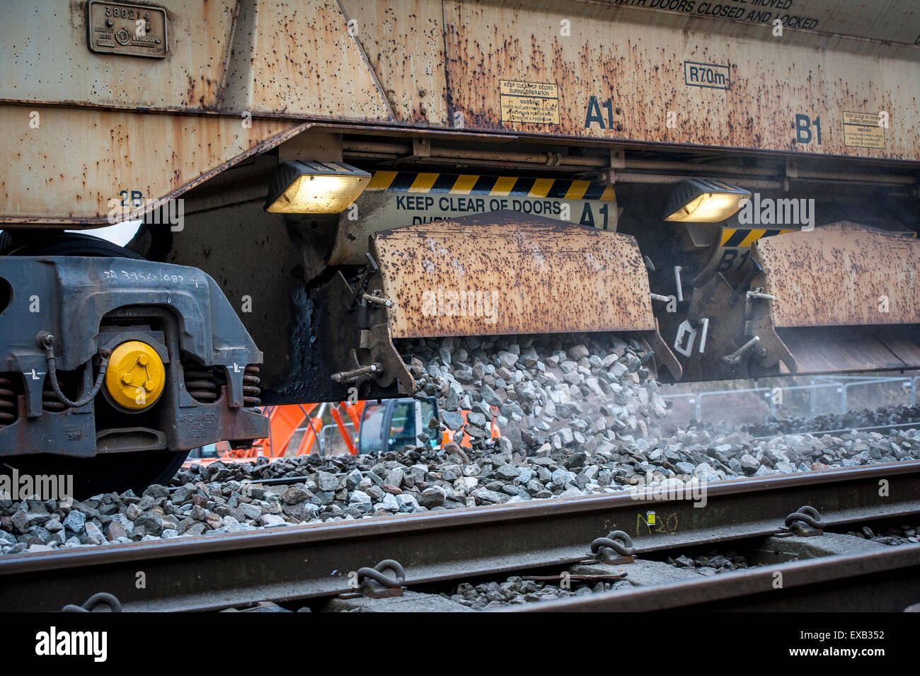 La guida della rete tramogge di zavorra zavorra posa durante la via di manutenzione su una linea ferroviaria in Inghilterra. Foto Stock