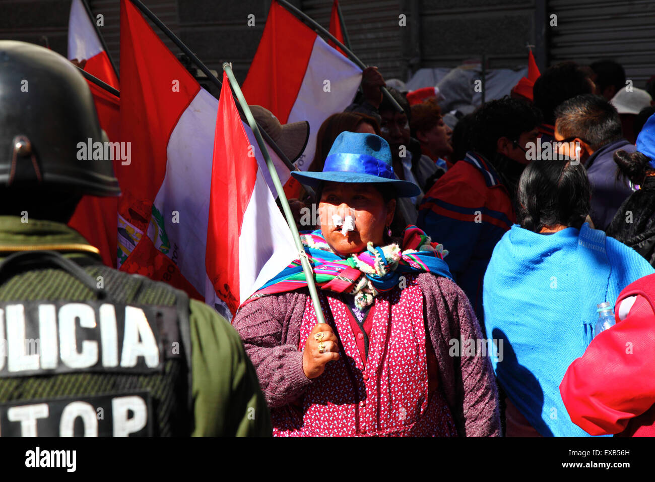 La Paz, Bolivia, 10 luglio 2015. Una protesta della zona Potosi con carta tessuta nelle narici (per ridurre gli effetti del gas lacrimogeno) durante una protesta del Comitato Civico Potosi e dei sostenitori. Sono a la Paz per chiedere al governo di mantenere le promesse elettorali fatte alla regione in passato. La polizia ha usato gas lacrimogeni per impedire ai manifestanti di entrare in Plaza Murillo le bandiere rosse e bianche sono le bandiere del dipartimento di Potosí. Credito: James Brunker / Alamy Live News Foto Stock