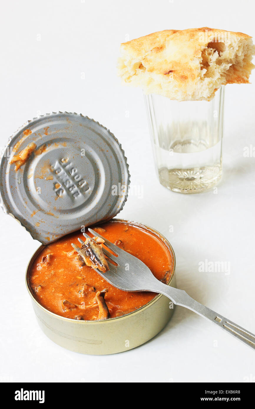 Conserve di spratto nella salsa di pomodoro con un forcellone in alluminio e vetro sfaccettate di vodka Foto Stock