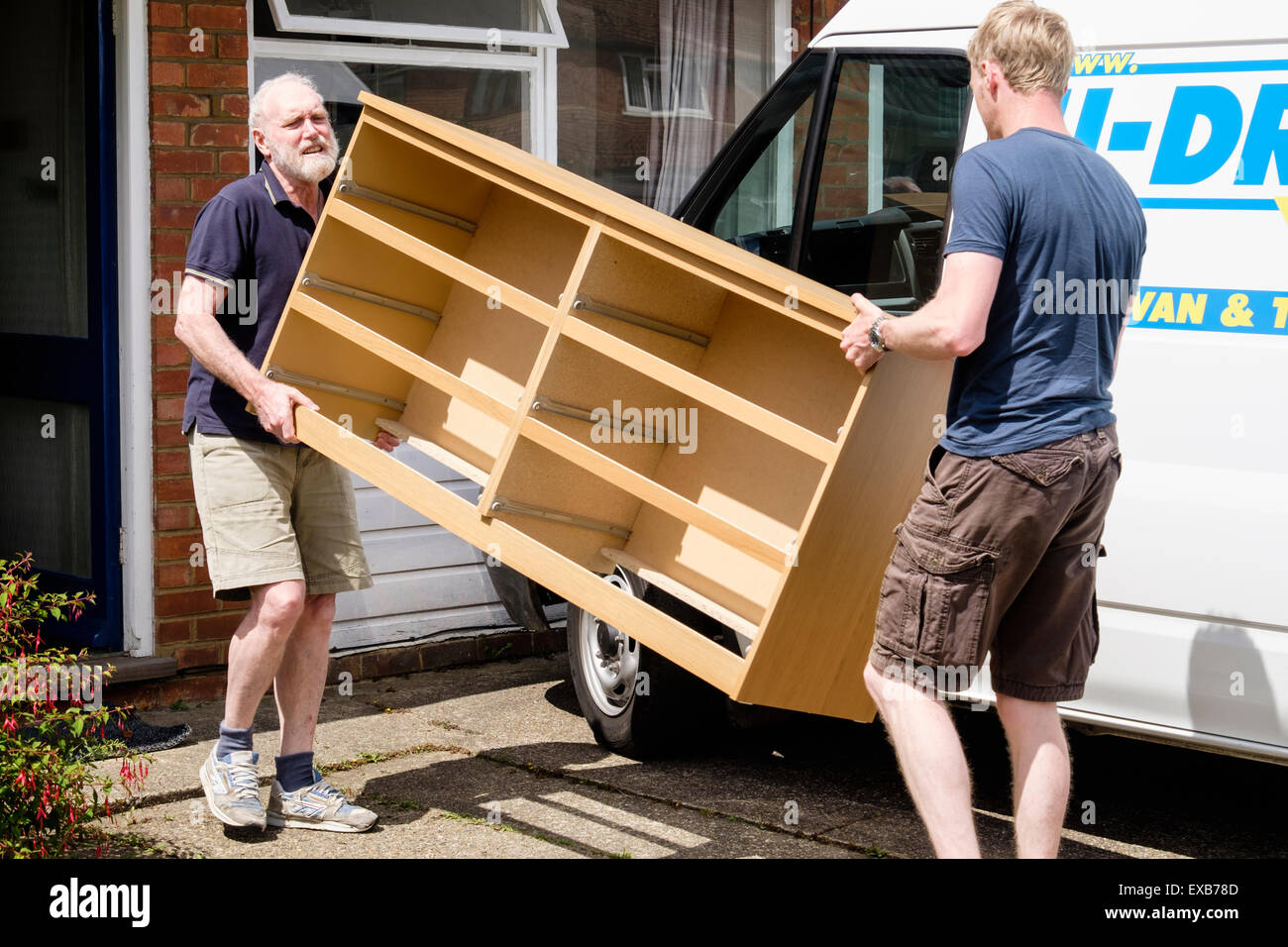 Aiutando il padre figlio per spostare mobili fuori di una casa che porta una cassettiera in un self-drive ingaggiato distacco van. Inghilterra, Regno Unito, Gran Bretagna Foto Stock
