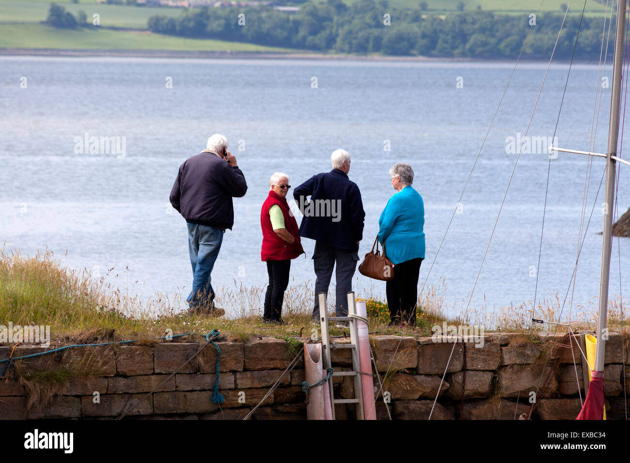 Gruppo di persone anziane in piedi sul molo, Charlestown, Fife Foto Stock