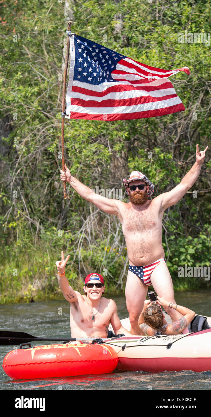 Floating il fiume Boise il 4 di luglio. L'uomo con la bandiera degli Stati Uniti, cappello e costume da bagno per celebrare il quarto su una zattera. Boise, Idaho Foto Stock