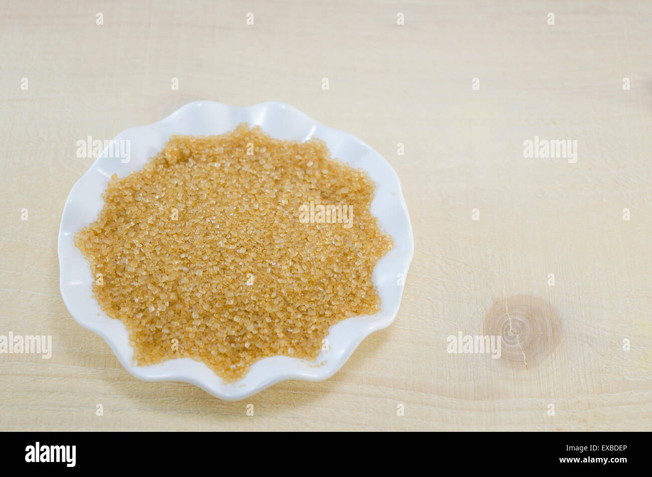Zucchero di canna in una piastra bianca su una tavola di legno Foto Stock