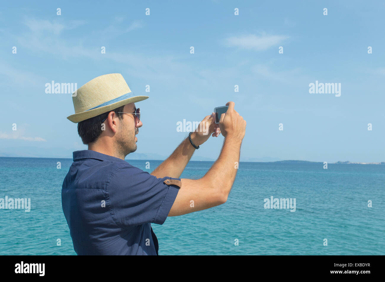 Uomo di scattare le foto con il suo telefono cellulare al mare Foto Stock