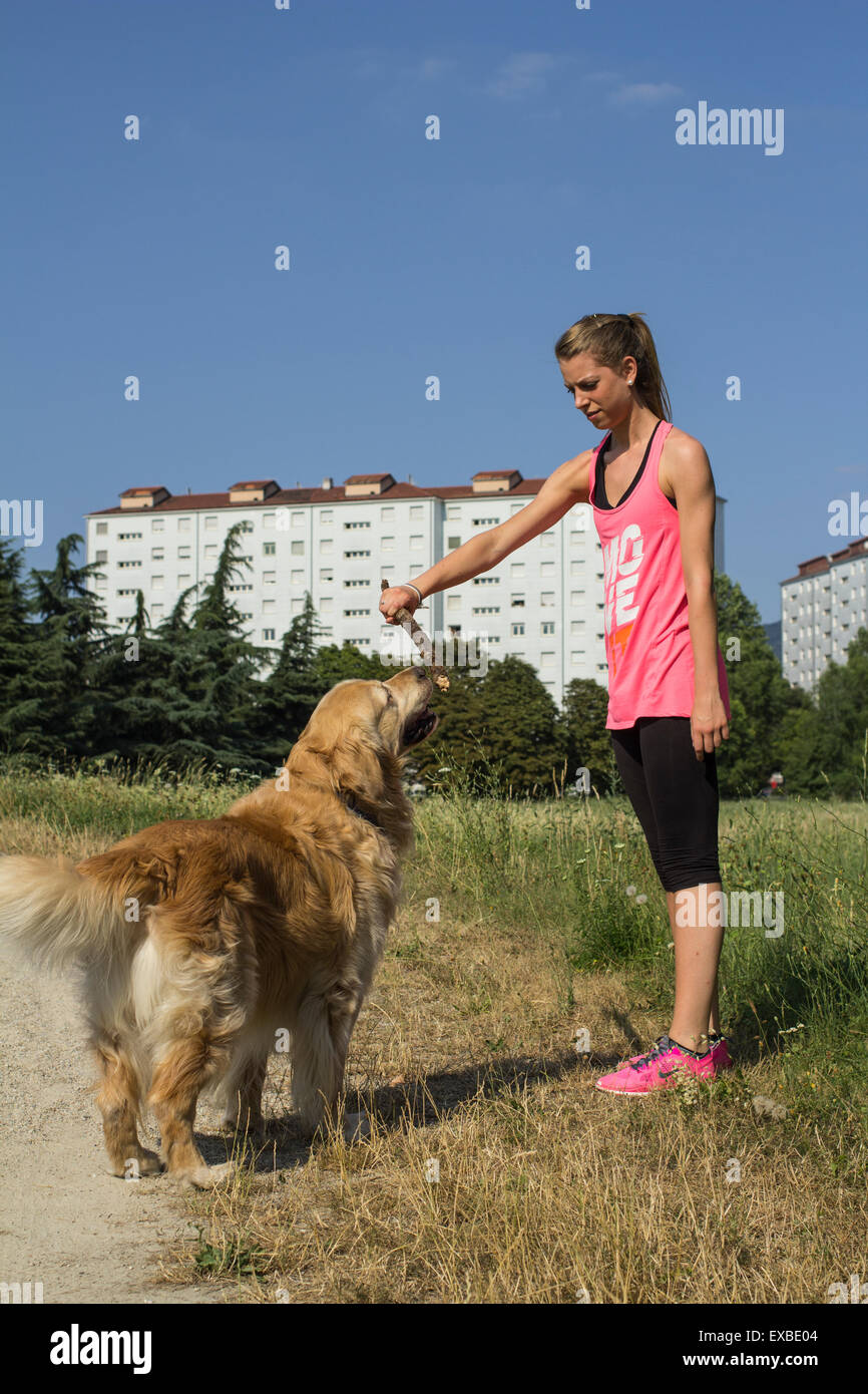 Ragazza bionda che gioca con il suo cane al parco Foto Stock
