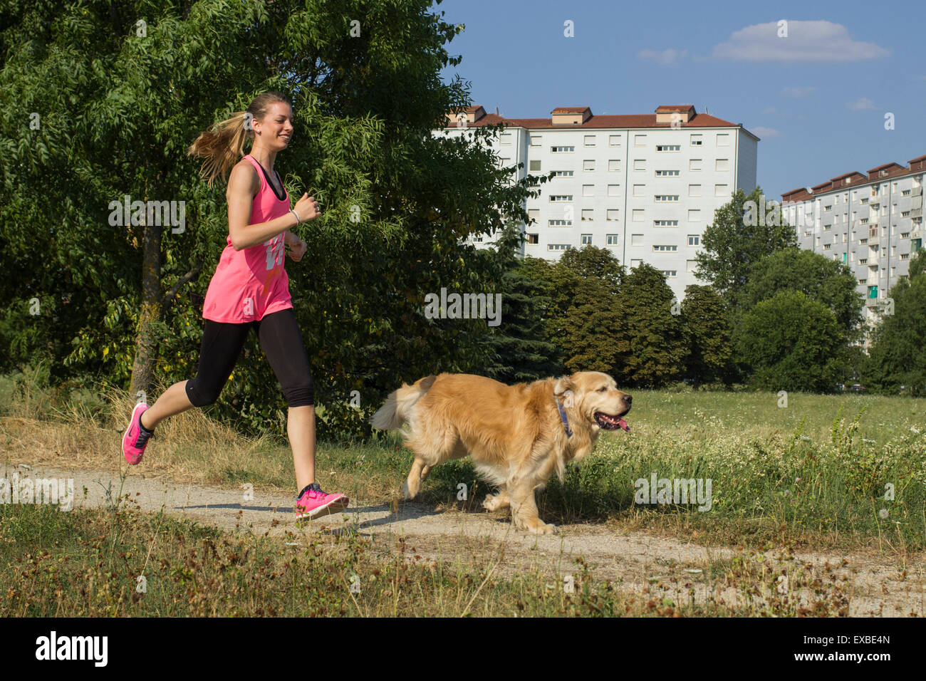 Ragazza bionda che corre al parco con il suo cane Foto Stock