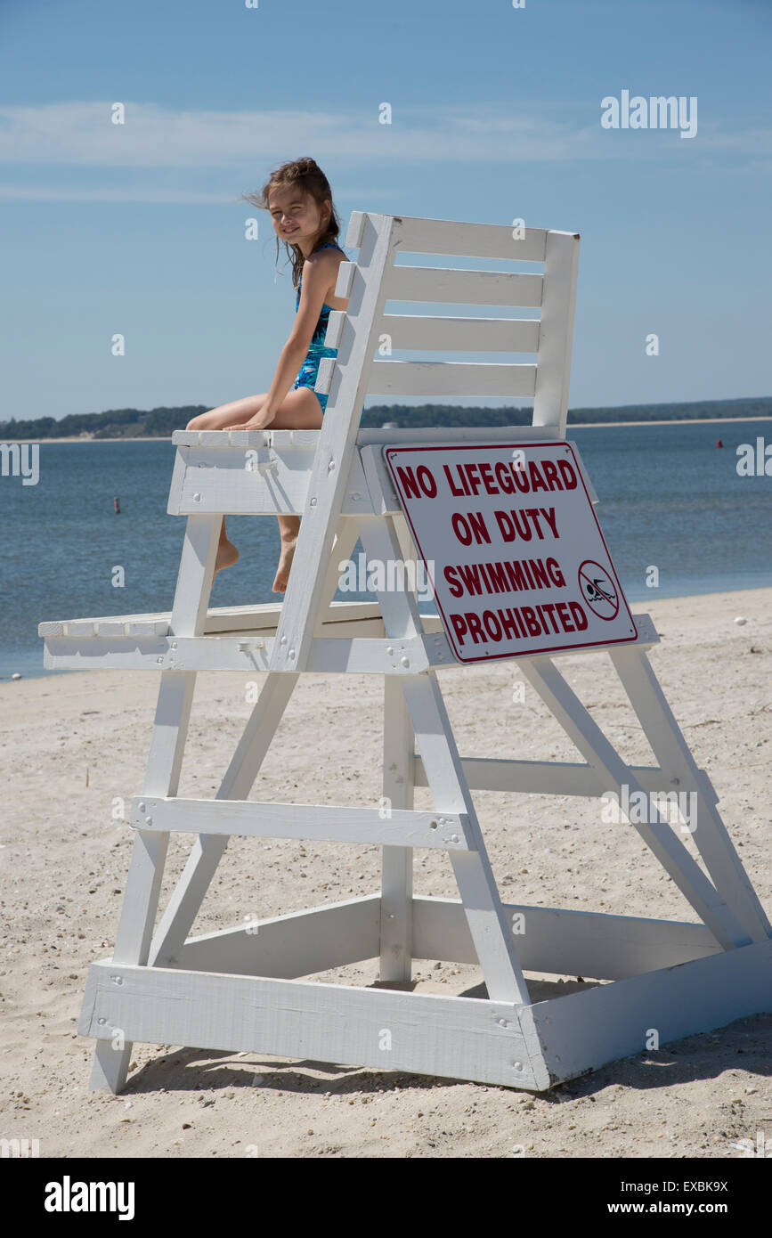 Ragazza giovane arrampicata su una sedia bagnino sulla spiaggia Jamesport  Long Island USA Foto stock - Alamy