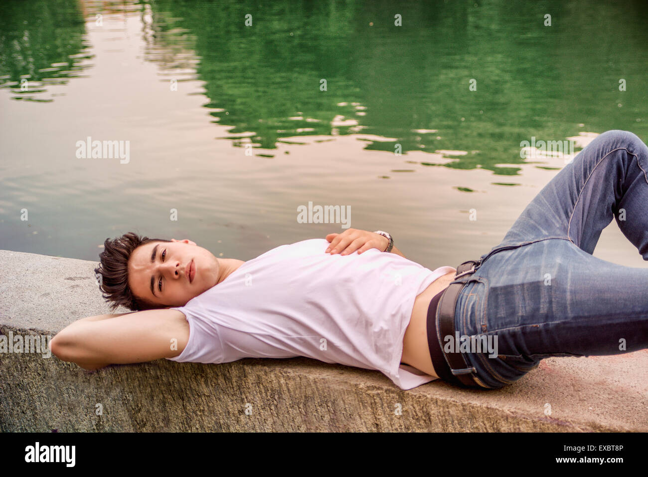 Bel giovane su un lago riva del fiume o le banche in una posizione soleggiata e tranquilla giornata, sdraiato Foto Stock