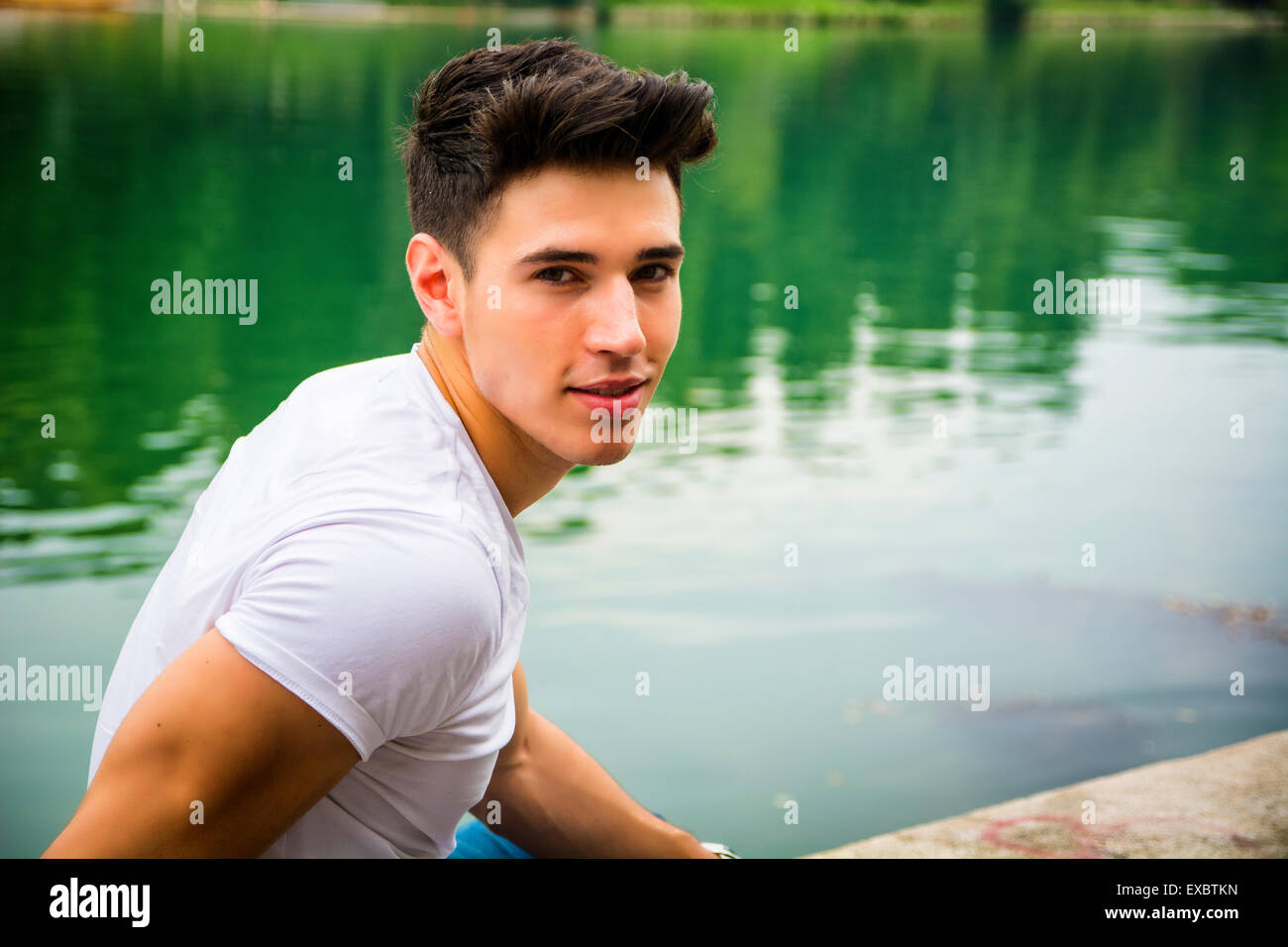 Bel giovane su un lago riva del fiume o le banche in una posizione soleggiata e tranquilla giornata, sdraiato Foto Stock
