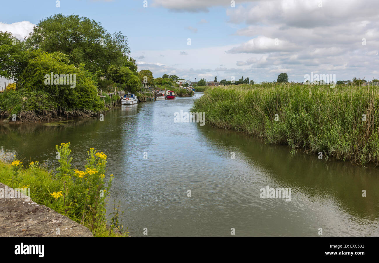 Fiume scafo con barche, alcuni derelitti, e le sponde del fiume con vegetazione ricoperta in una bella mattina d'estate. Foto Stock