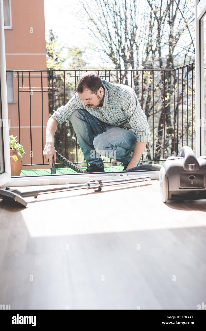 Bello elegante uomo utilizzando hoover a casa Foto Stock